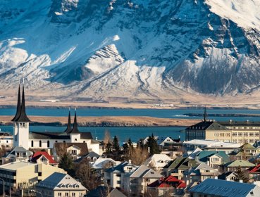 Village buildings and houses with mountain covered in snow in background located in Reykjavik