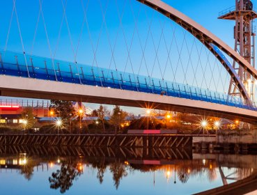 Milenium Bridge at dusk with streetlights turning on and reflecting the image in the water below