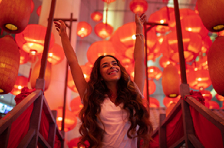 Woman raising her hands in joy, surrounded by red Chinese lanterns