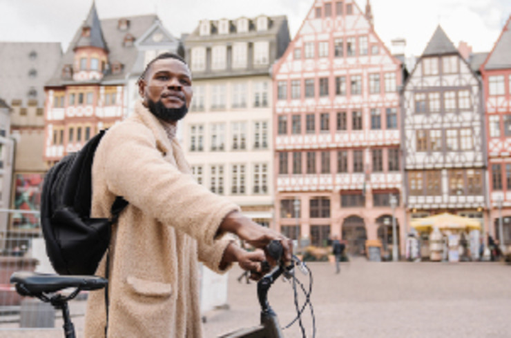 man on a bike in front of buildings in frankfurt