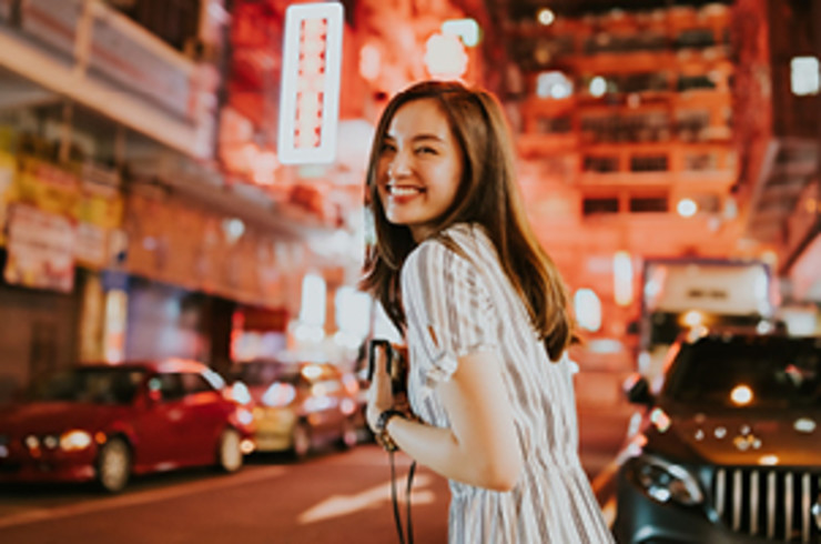 Lady smiling in Hong Kong street with bright lights in the distance