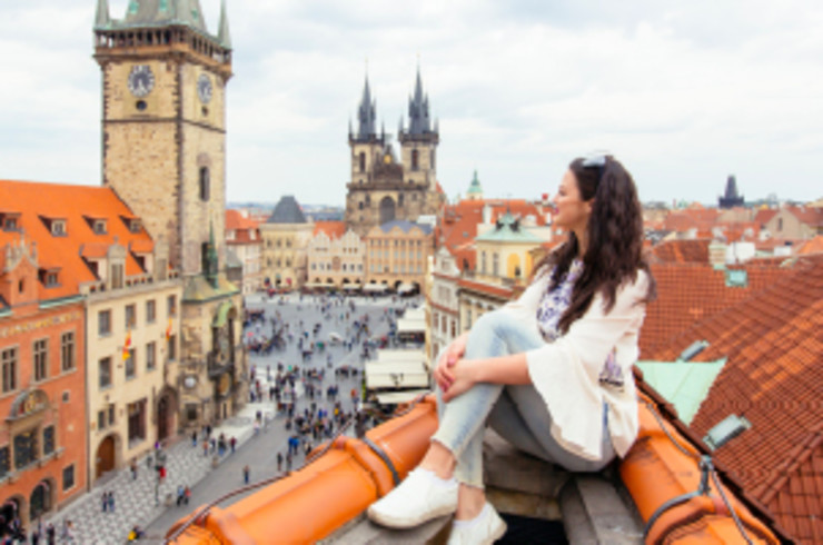 lady sitting on top of building overlooking city in prague
