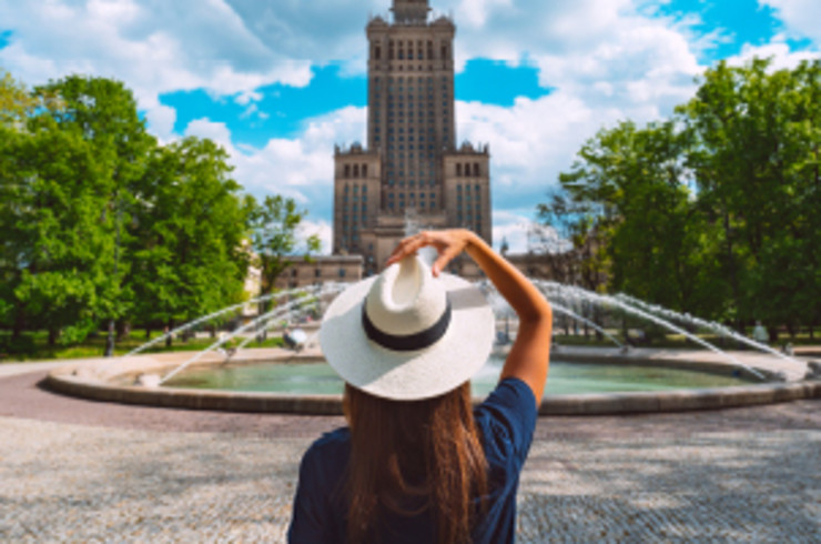 lady with white hat standing outside fountain in warsaw