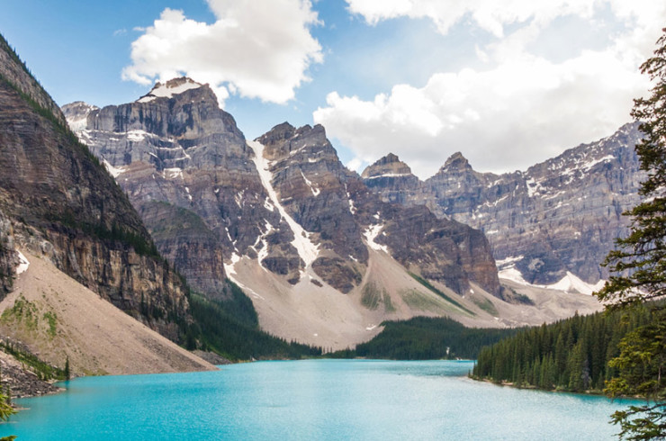 Pine trees and rocky mountains framing a bright blue lake