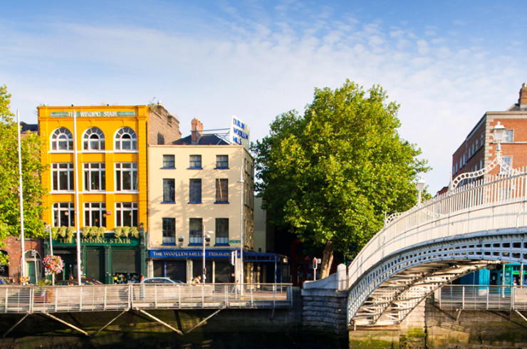 White arch bridge over a smooth reflective river with multi-storey buildings along the side