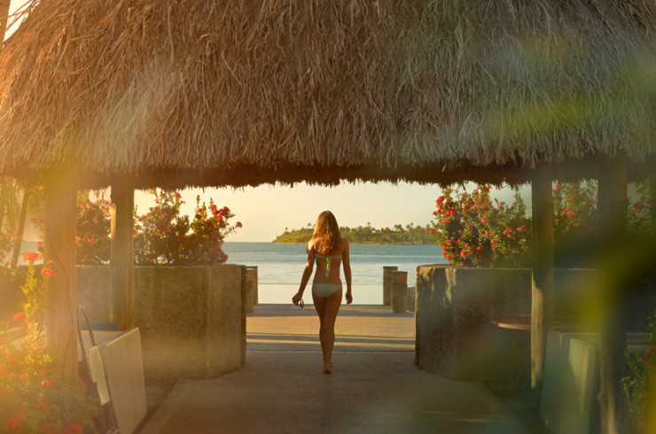 Woman in a white bikini under a thatched gazebo