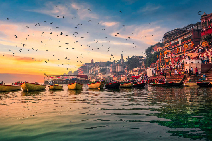Rowboats at an Indian dock with hundreds of birds circling overhead