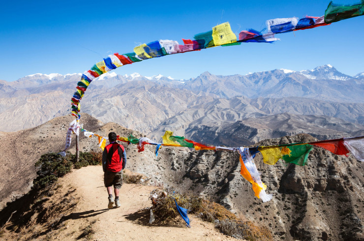 Man standing on a mountain standing beneath a string of flags