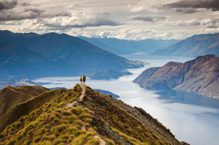 Couple standing on a grassy hill overlooking mountains and rivers
