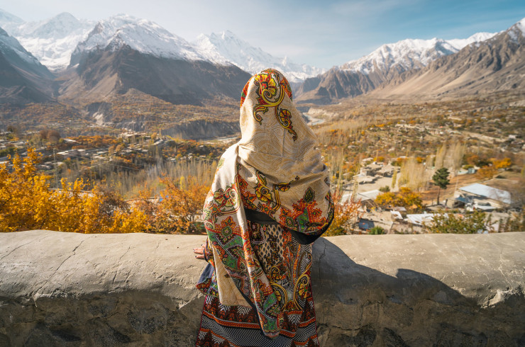Woman wearing a colourful Burka looking out over Pakistan