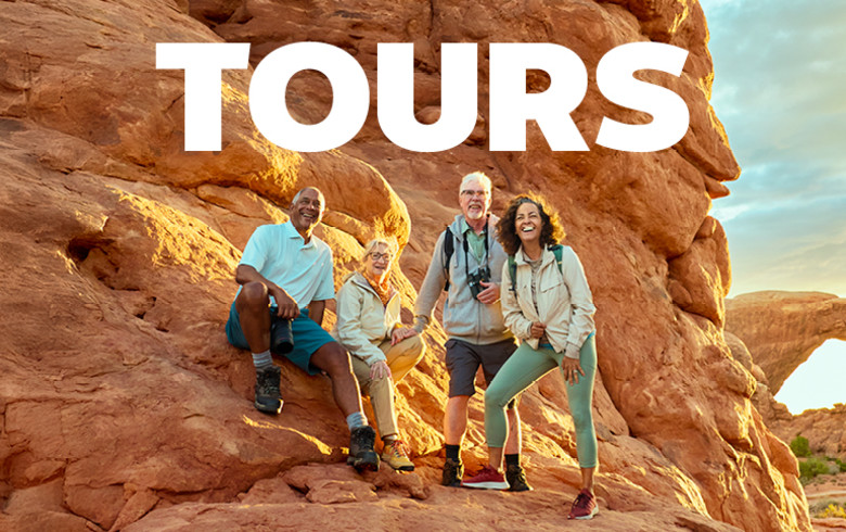 Tours - 4 middle aged people sitting on a rock wall