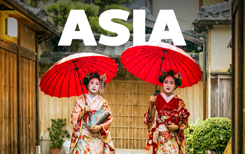 Asia - two Geishas carrying red parasols in the rain