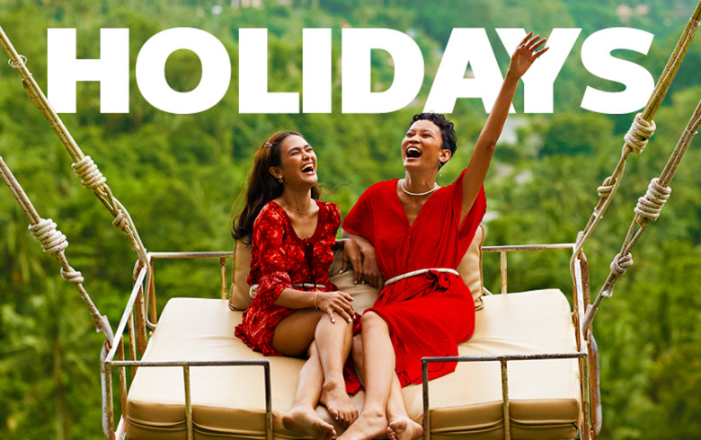 Holidays - two women in red clothing cheering on a swing in Bali
