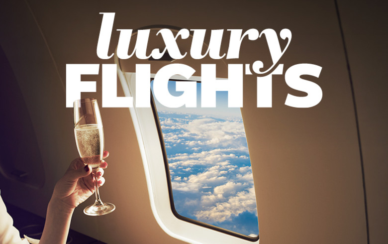 Hand holding a wine glass next to a plane window featuring luxury flights