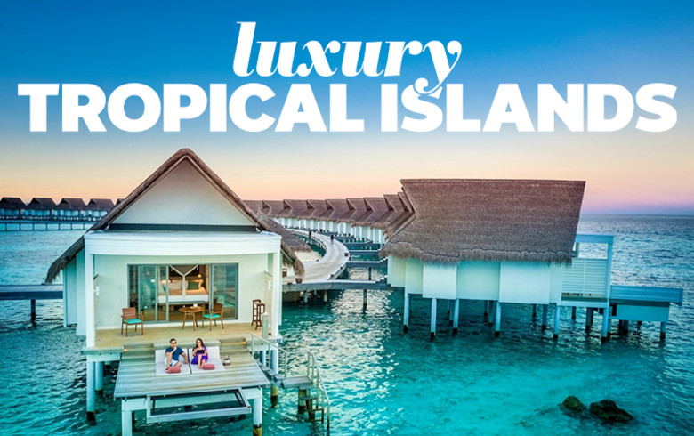 Couple relaxing on an overwater villa deck at sunset for luxury tropical island holidays