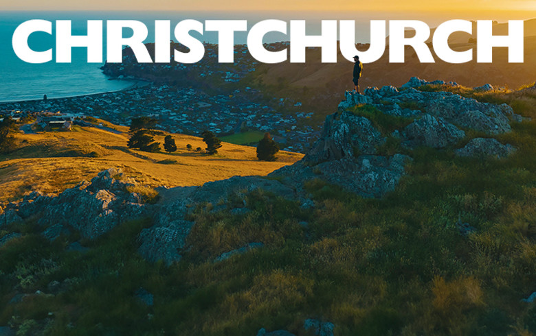 Christchurch - person standing on a rocky outcrop looking out at rolling green fields in New Zealand