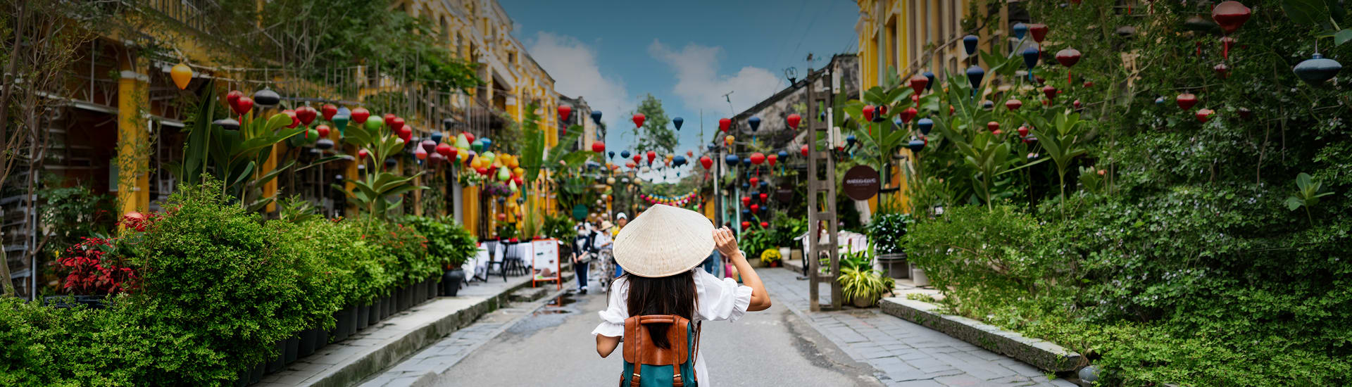 A person with an Asian hat and backpack on a bright road