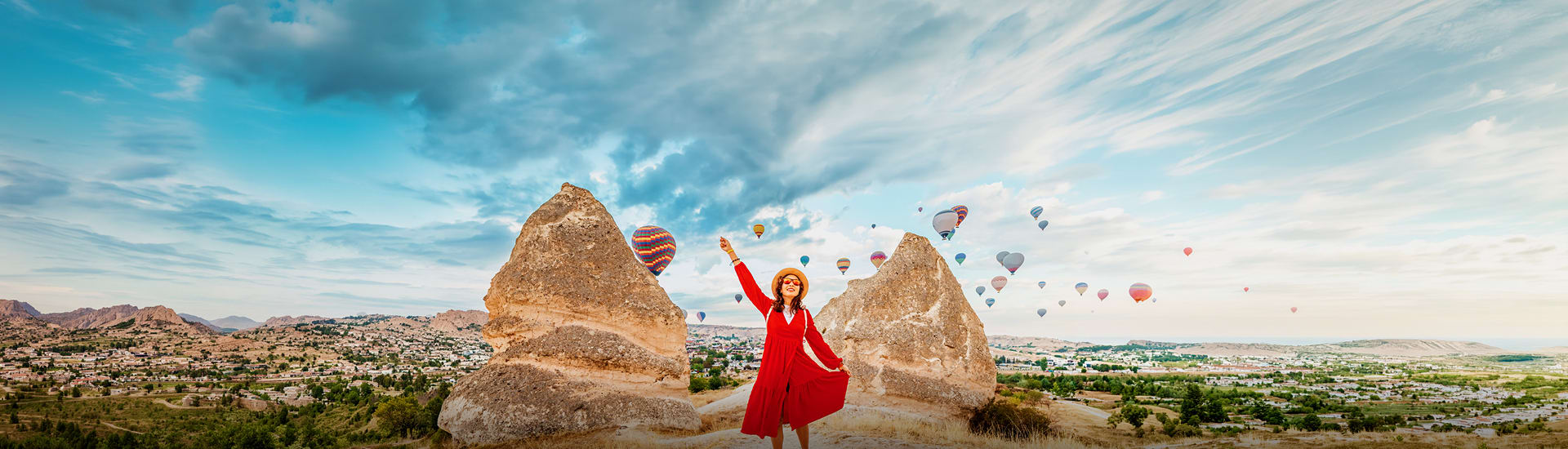 A woman in a red dress in Turkey with hot air balloons in the background