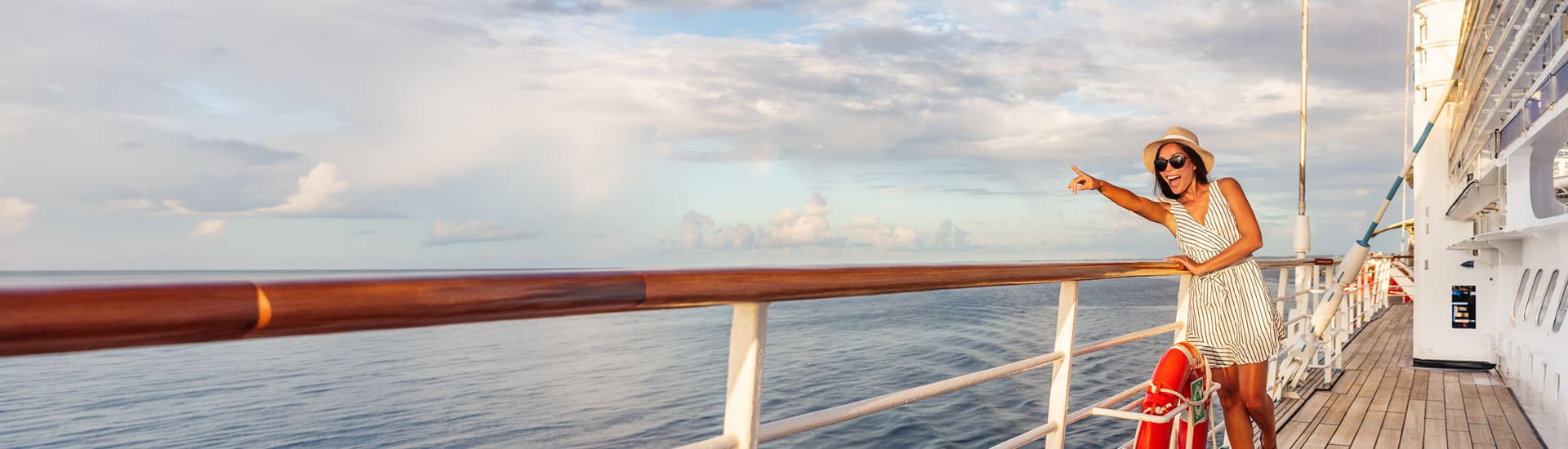 A woman on board a ship pointing at something off the boat