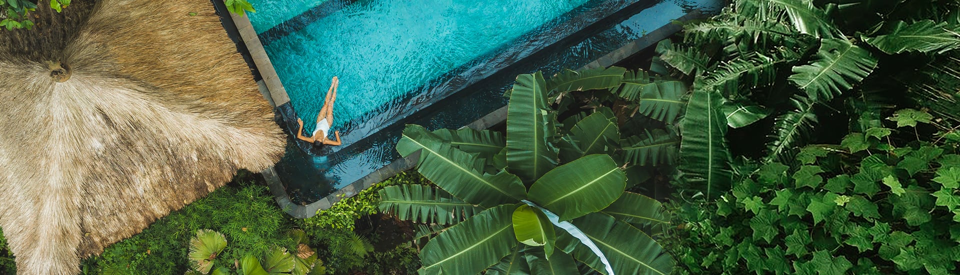 Top down view of a woman in a white bikini relaxing in a pool in Bali