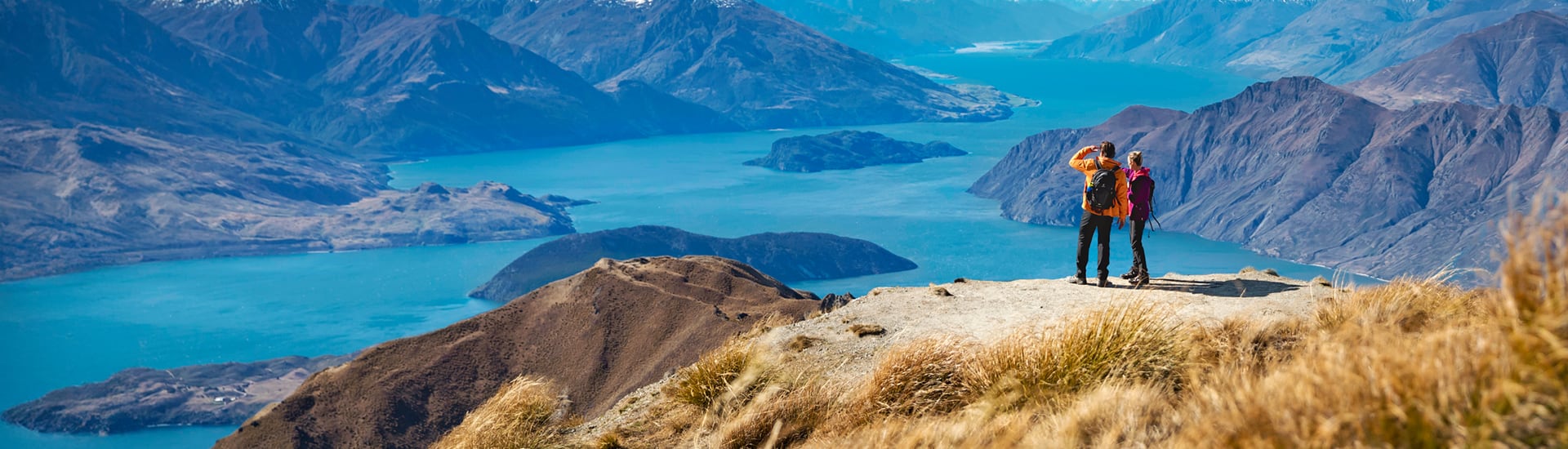 Couple standing at the top of a mountain looking out at a wide river in New Zealand