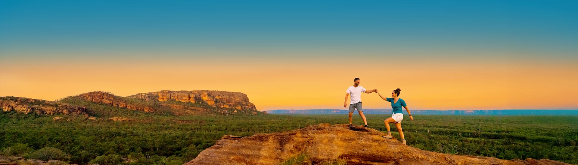 Couple climbing a rock overlooking the Australian Outback