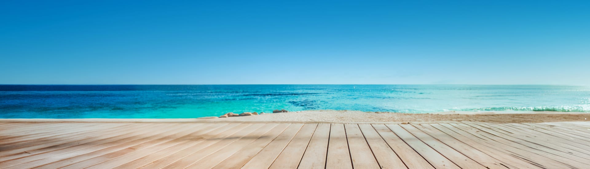 Wooden pier at the beach on a clear day with bright blue, clear ocean water