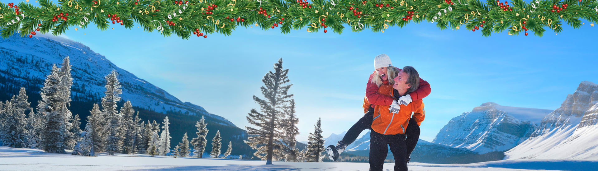 Couple playing in the snow framed by pine trees and snow covered mountains