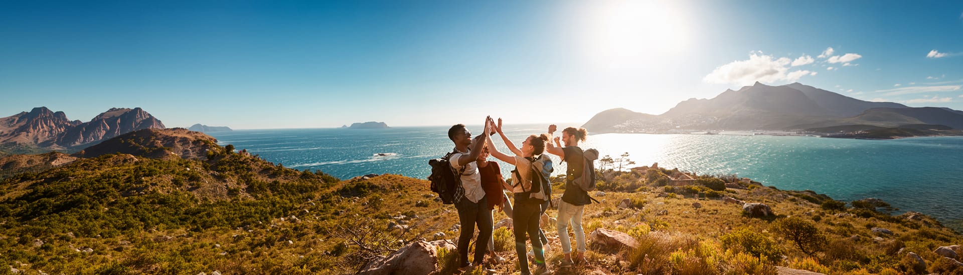 Four hikers celebrating by the ocean