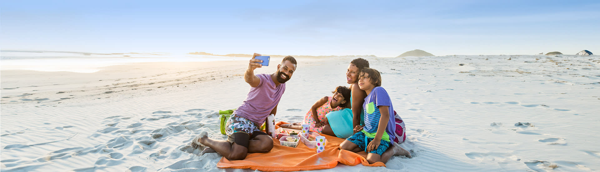 Family taking a beach selfie during a seaside picnic