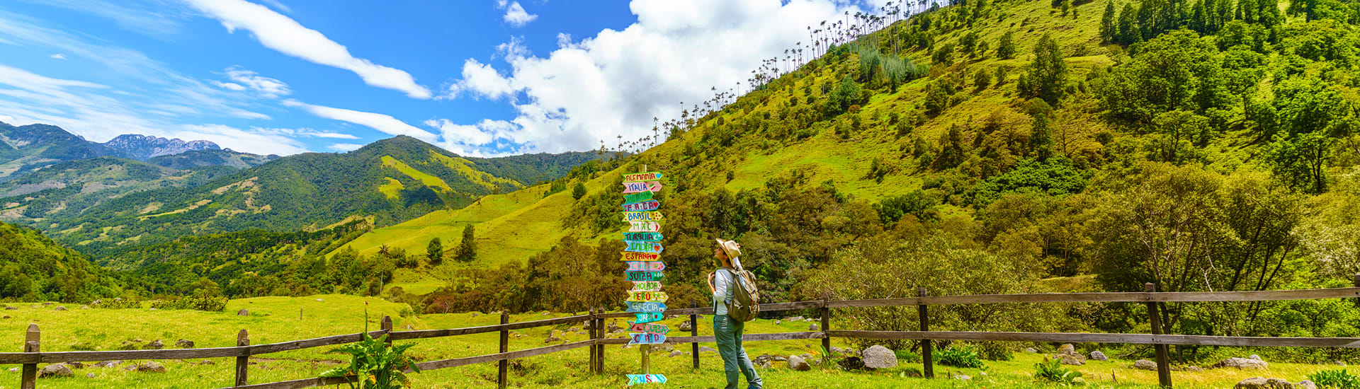 A person with a hat on looking at signs to different destinations hiking