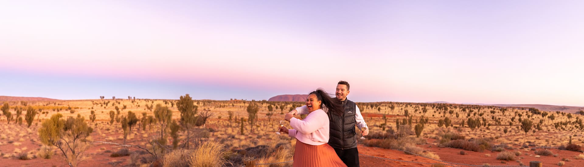 A couple enjoying champagne in front of Uluru