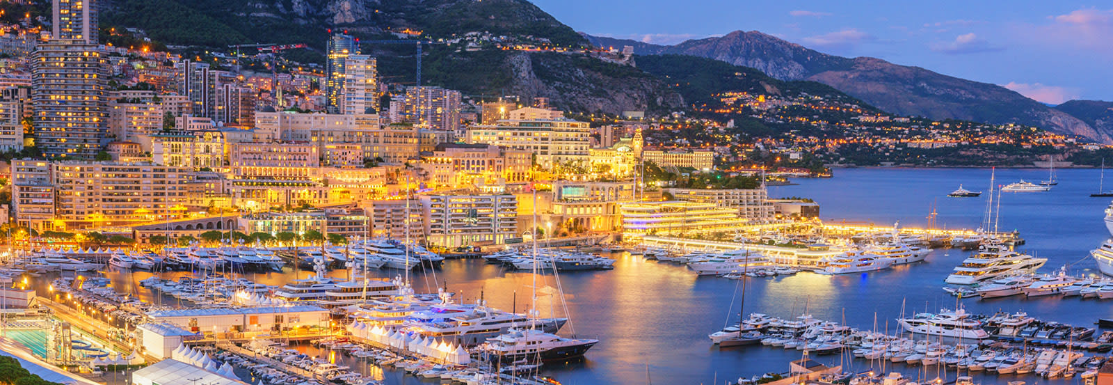 Marina lite up with city lights dusk time, Monaco