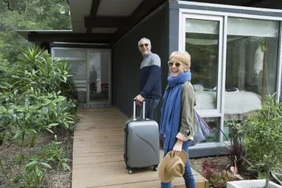 Couple arrive at vacation home with suitcases