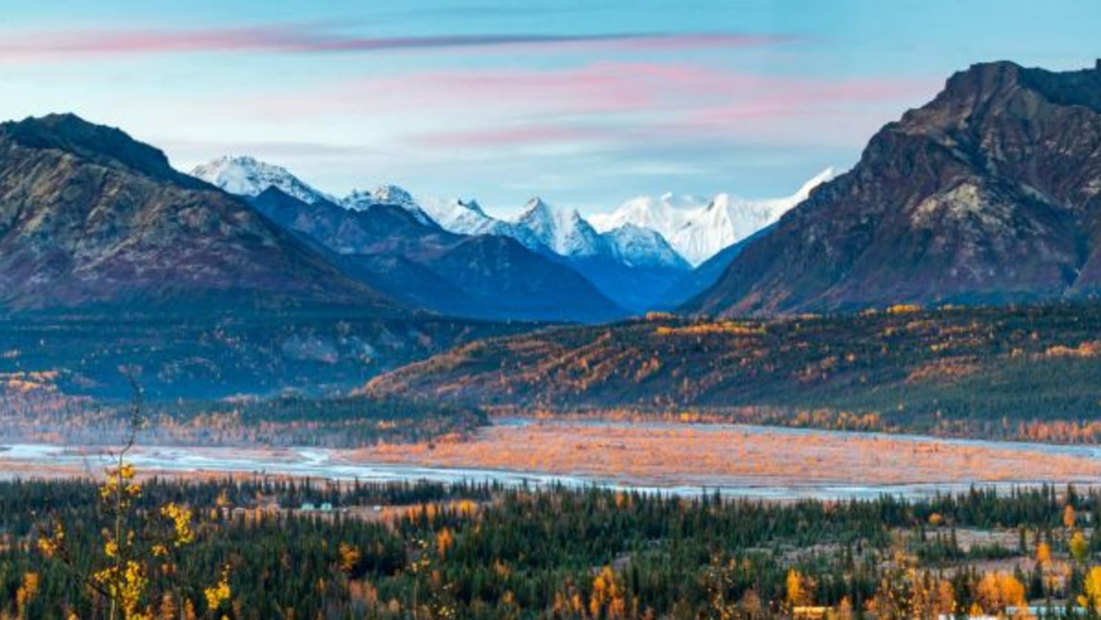 Snow-capped mountains in the background with autumnal foliage in the foreground.
