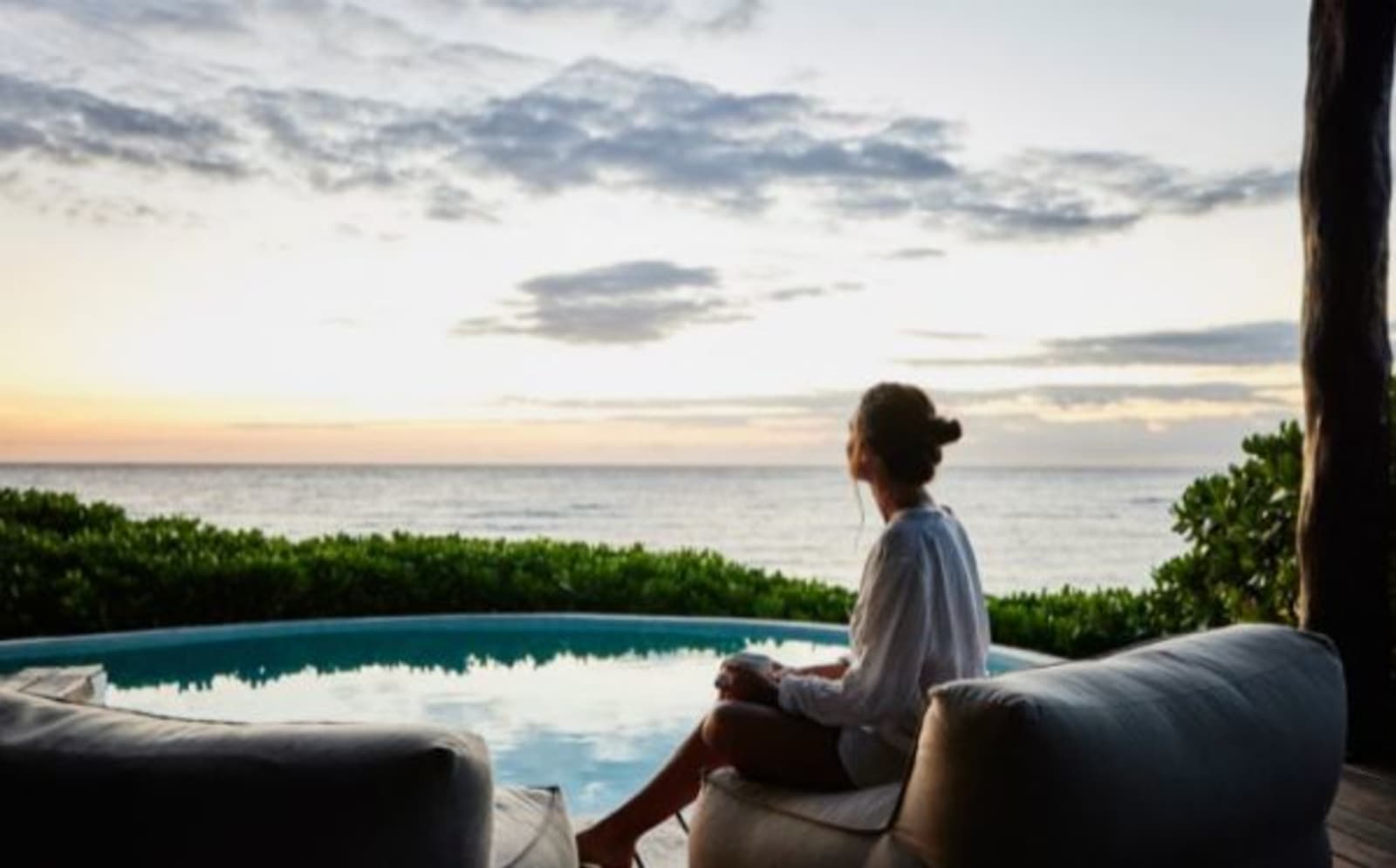 woman sitting by pool with ocean behind
