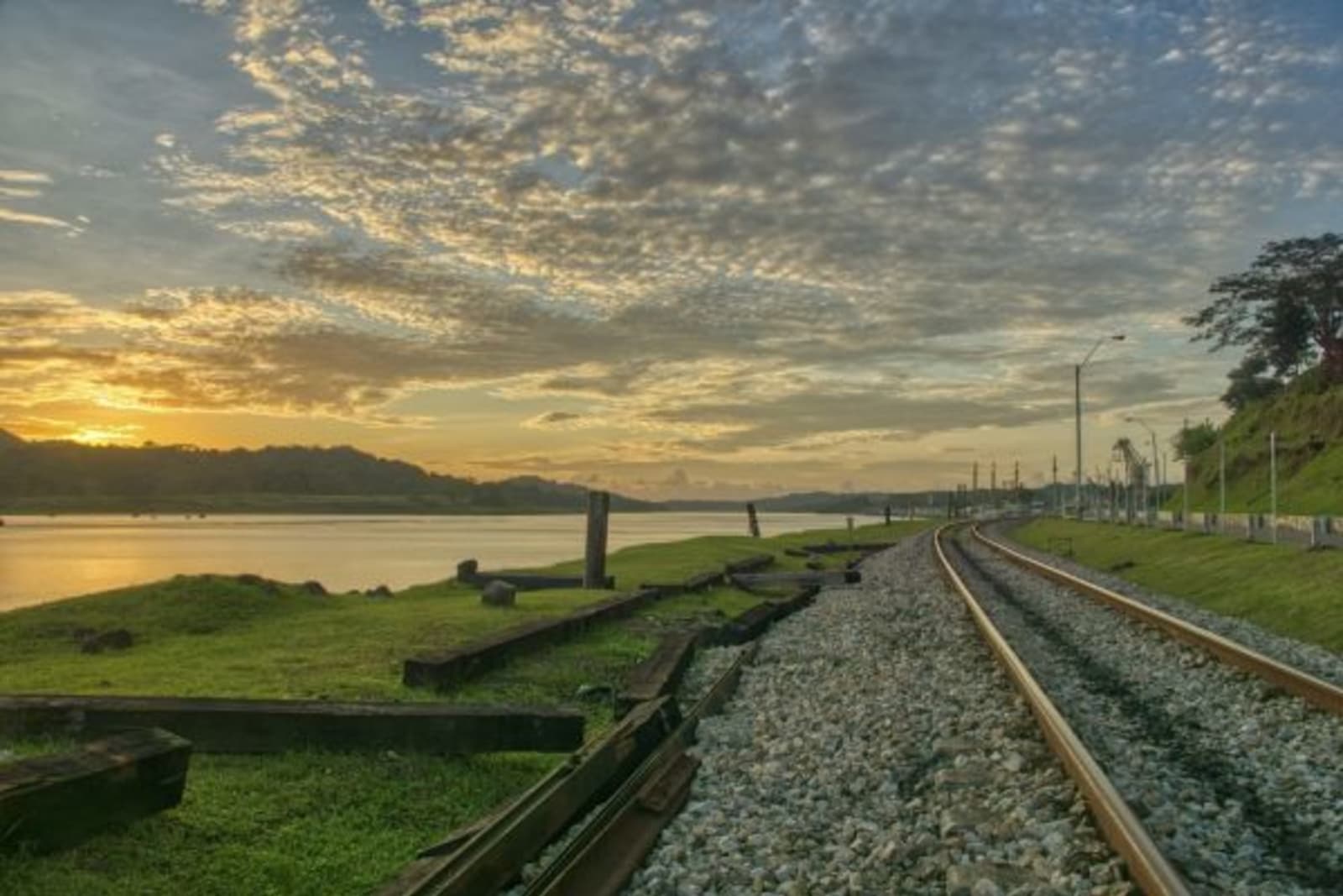 Sun setting over mountain ridge looking over a lake and railway tracks