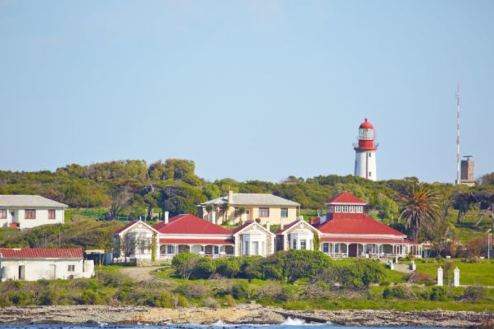 House with a lighthouse in background through the trees