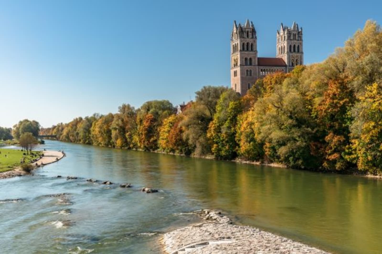 River with trees along the side and a church behind the trees