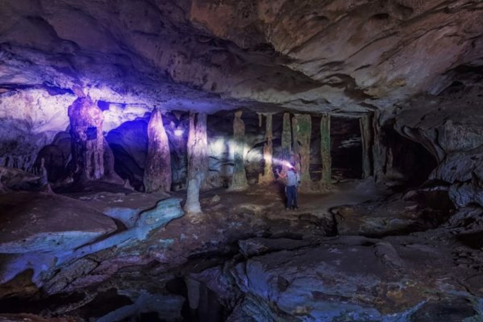 People in a cave with a torch shining on cave wall