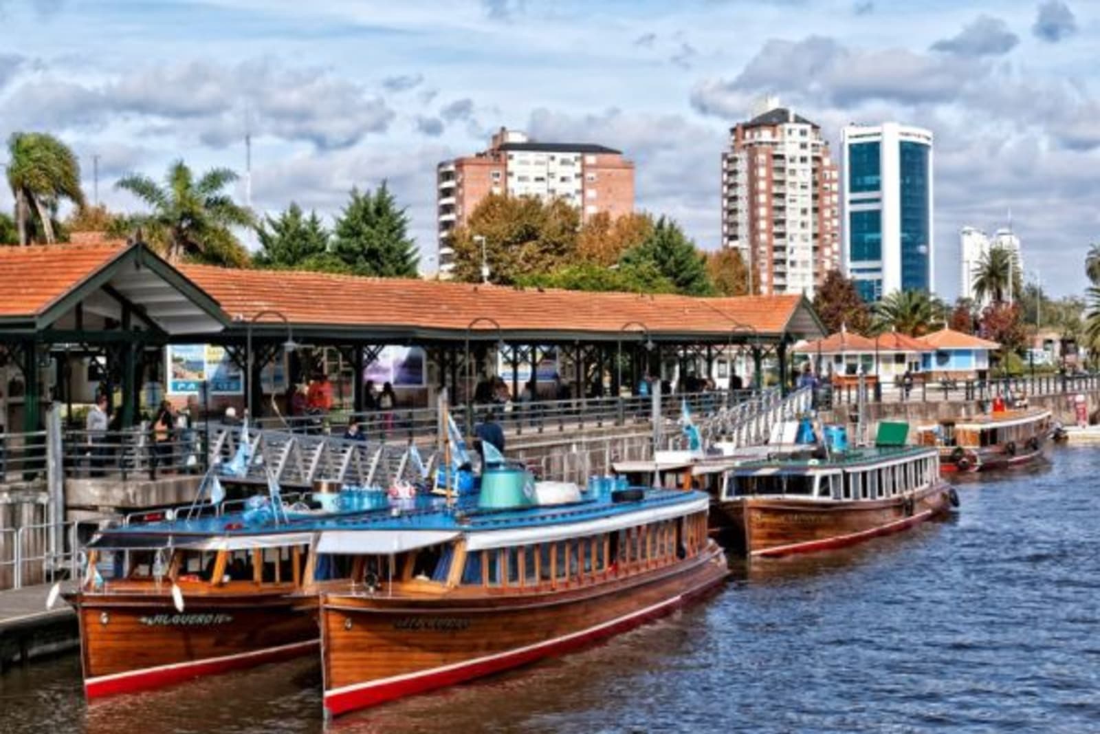 Sail boats at port in Tigre next to land with city buildings in background