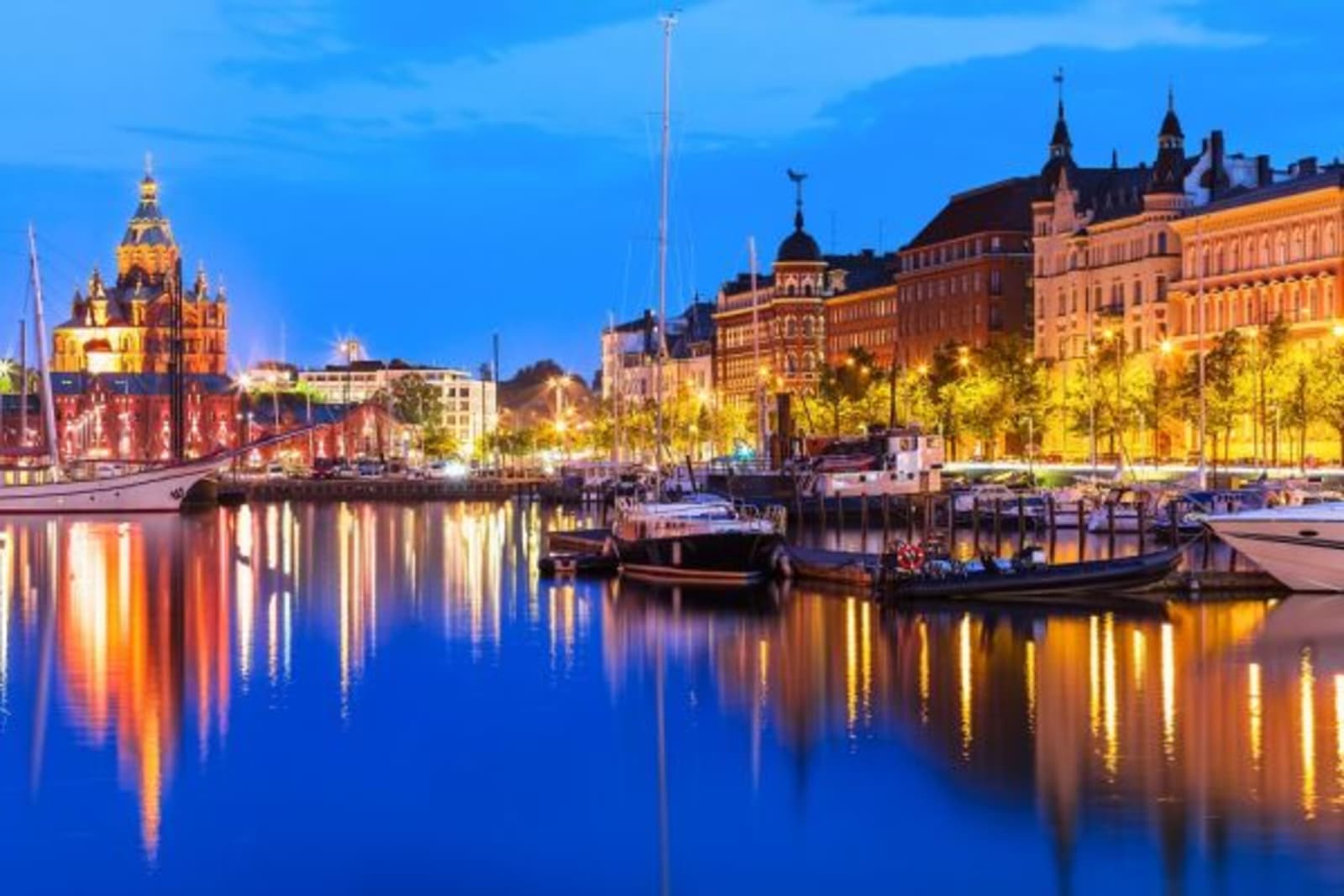 Boat harbor at night with city lights reflecting on canal