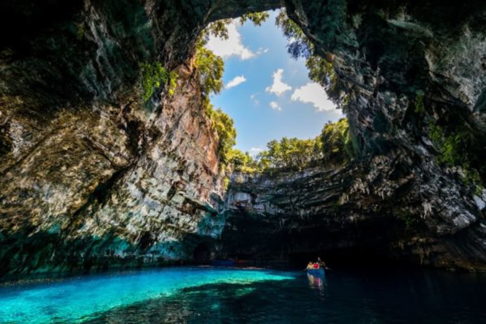 People swimming in clear water in the bottom of a cave