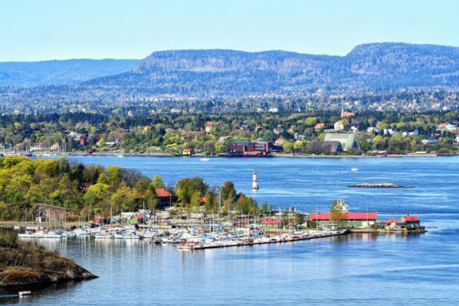 Distant image of a boat yard in Oslo with mountains in background