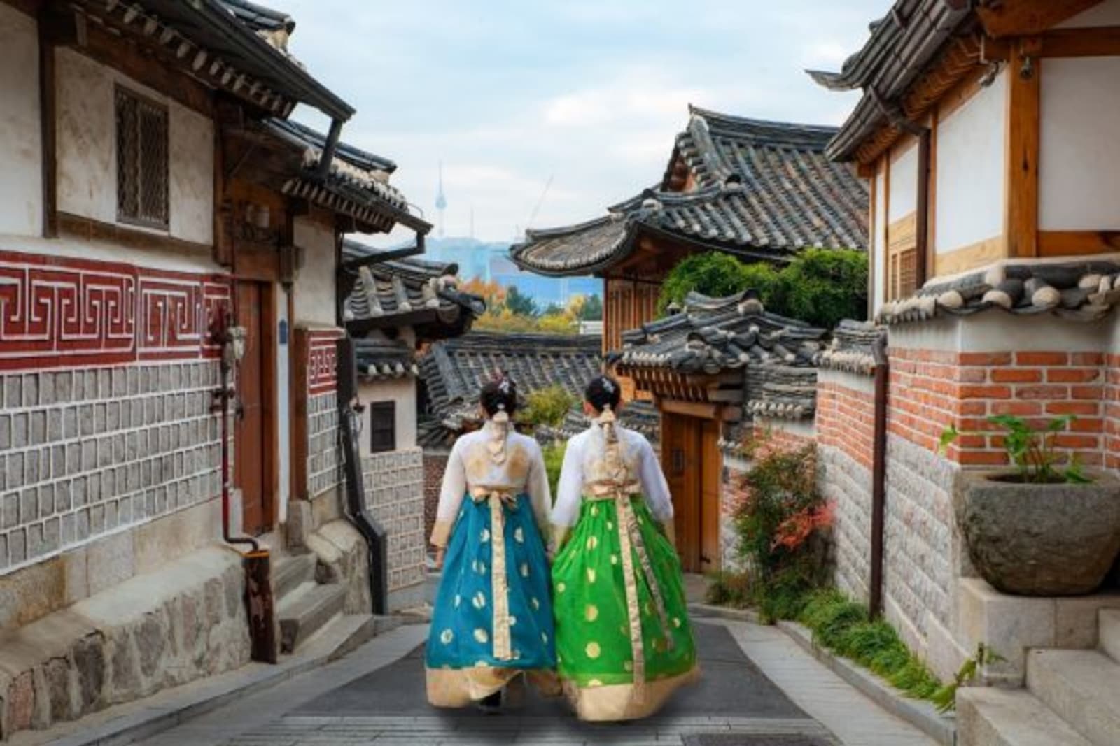 Two traditionally dressed females walking through traditional village in the streets of Seoul