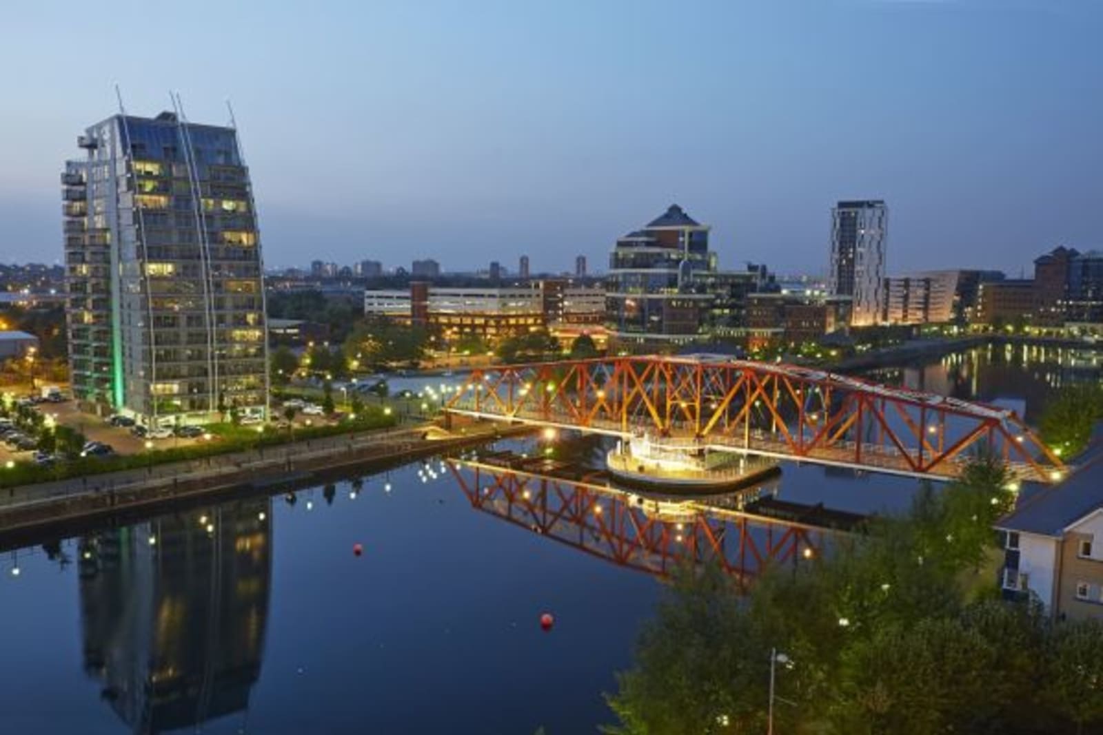 Red bridge over water leading to city buildings