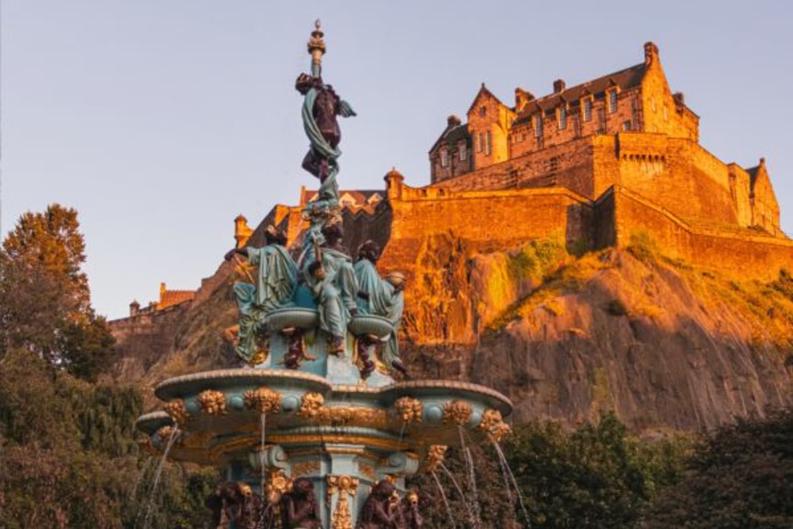 Statue on a water fountain in front of sun gazed castle
