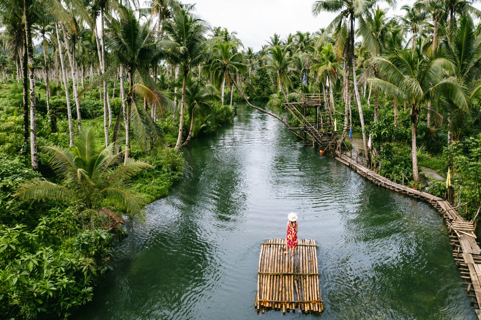 Woman on a wooden raft on a river among tropical trees, Philippines