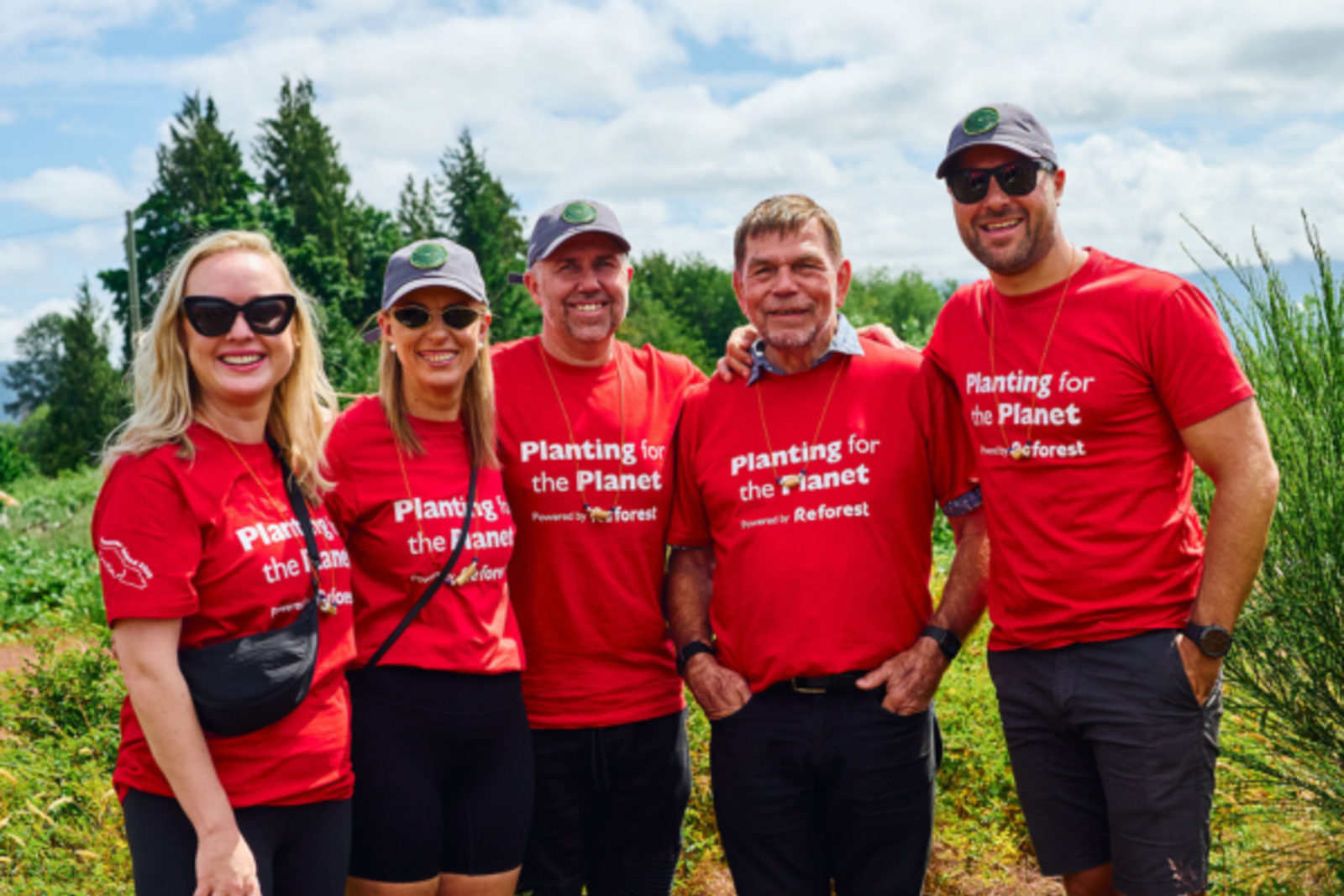 Flight Centre staff wearing Planting for the Planet shirts in a field
