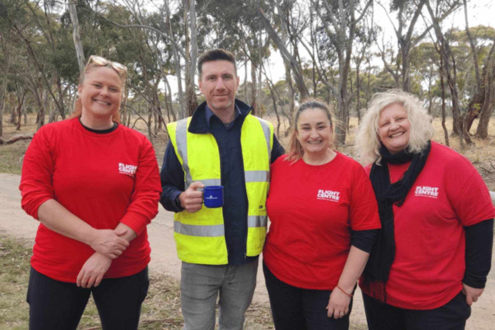 Flight Centre staff and a man in high-vis standing in the bush